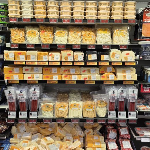 Deli cooler stocked with cheese, snack sticks and packaged dairy