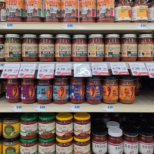 Grocery shelf lined with jars of salsa and sauces